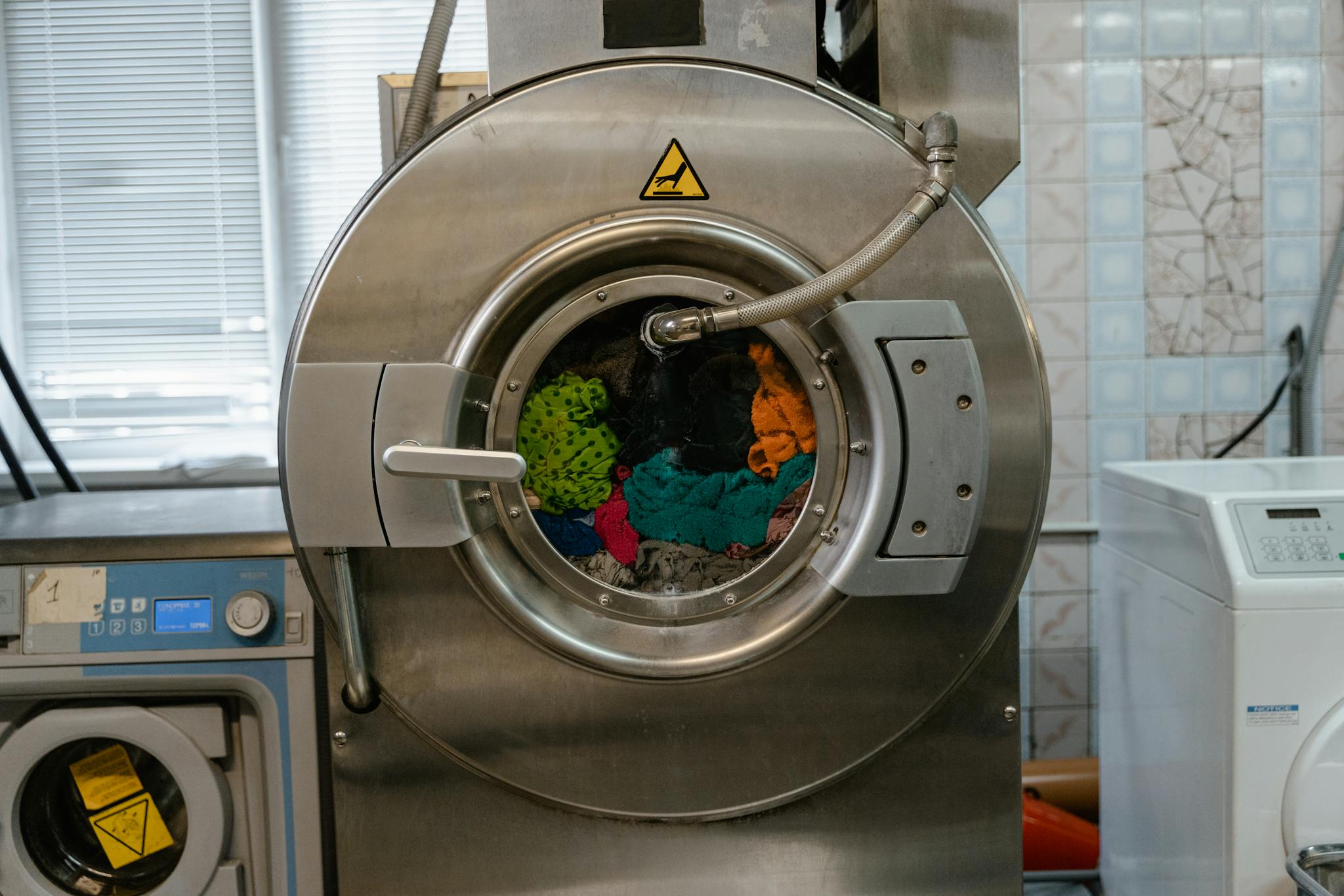 Servicio de mantenimiento y repación en toda España - Reparaciones de electrodomésticos A close-up of an industrial washing machine operating in a laundry facility.