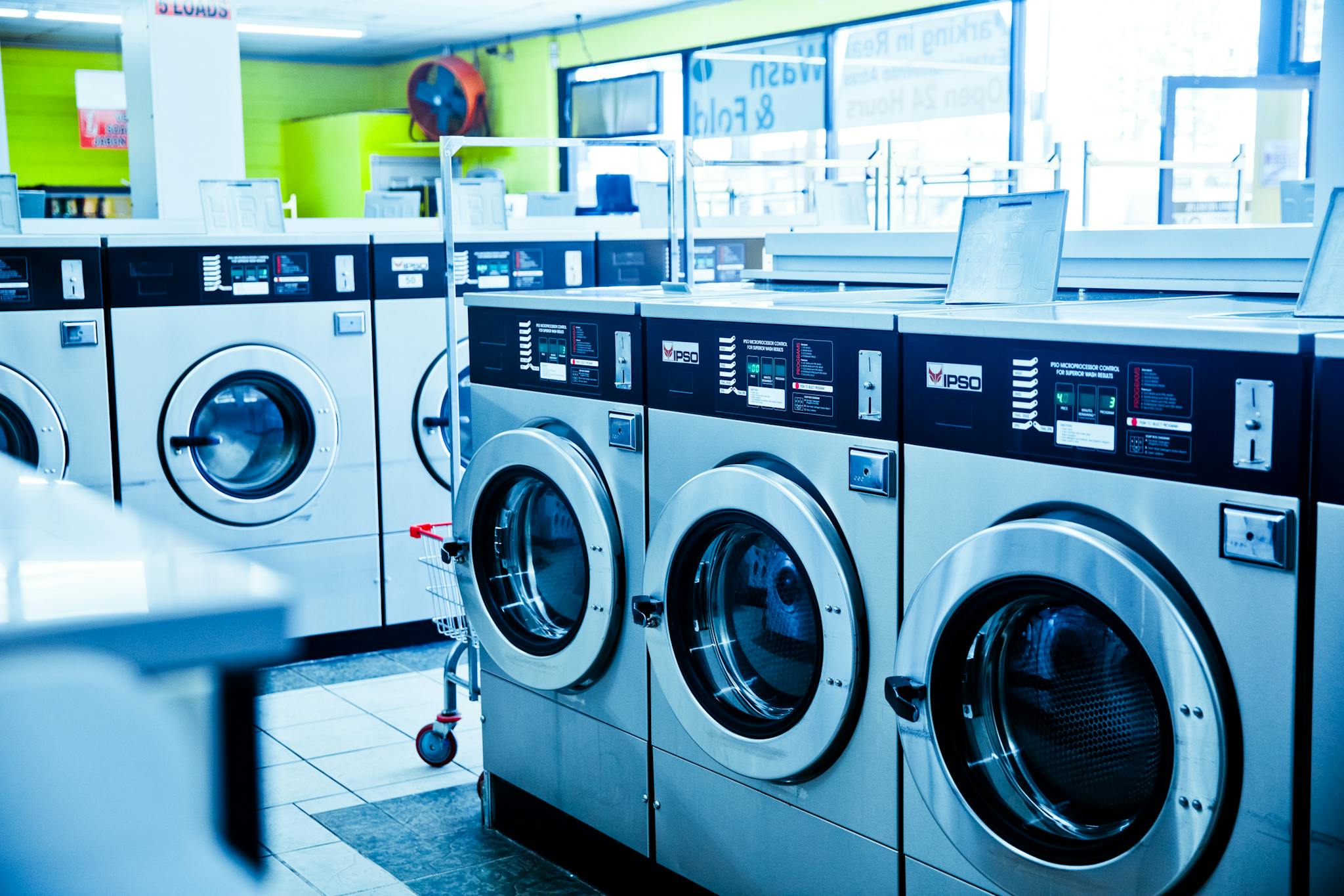 Servicio de mantenimiento y repación en toda España - Reparaciones de electrodomésticos Contemporary laundromat showcasing a row of industrial washing machines for public use.